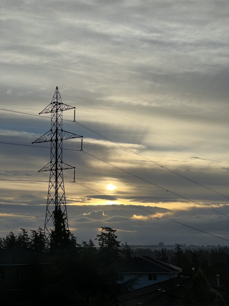 A picture of a skyline on a cloudy morning. Just barely can you see the sun poking through the clouds.